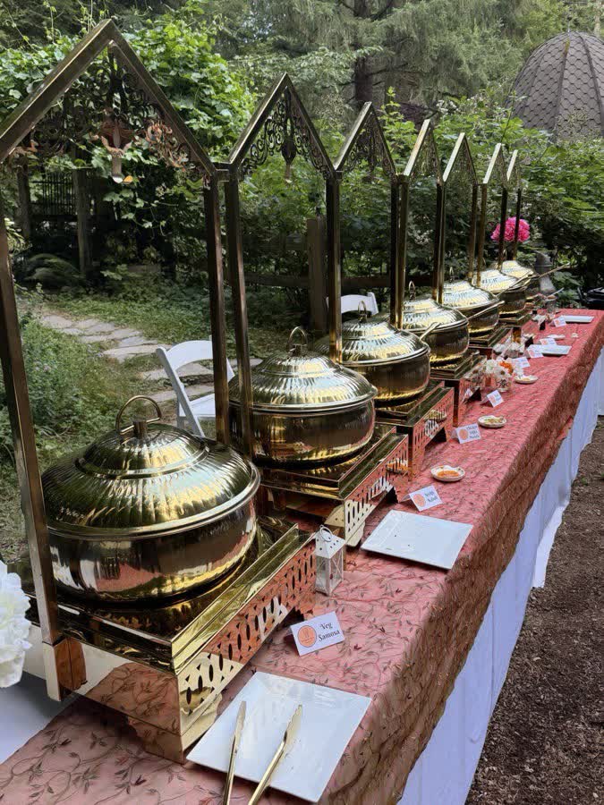 Indian wedding buffet set up outdoors with chafing dishes